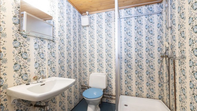 Bad i underetasje også fra byggeår. Gulvbelegg på gulv, servantinnredning og dusjkabinett.