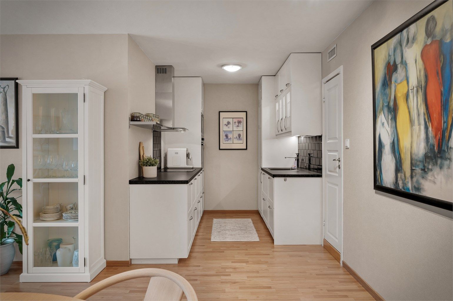 Innbydende og klassisk hvit kjøkkeninnrednig med sort benkeplate samt matchende veggfliser over.