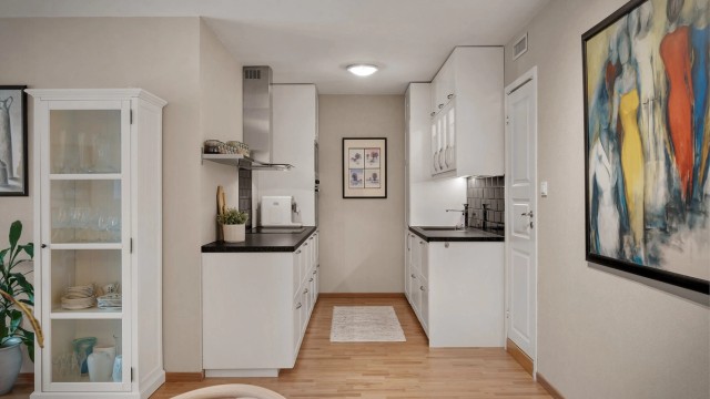 Innbydende og klassisk hvit kjøkkeninnrednig med sort benkeplate samt matchende veggfliser over.