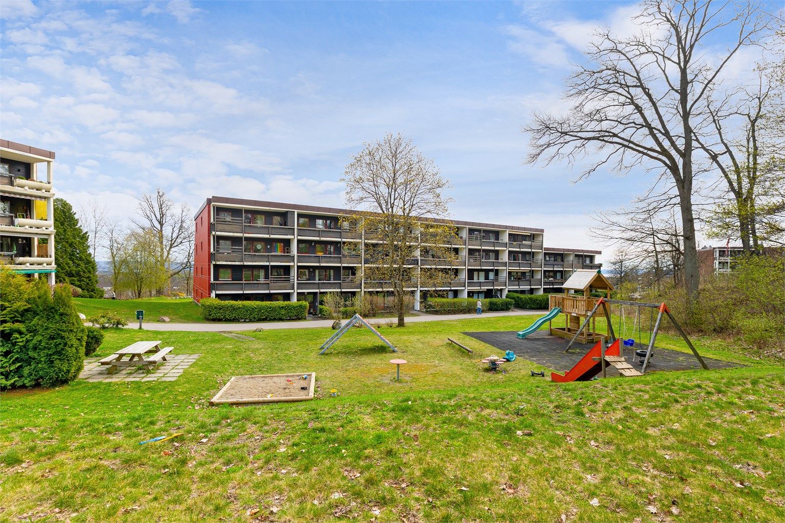 Store, grønne fellesarealer med lekeplass og sittegrupper, pent opparbeidet for beboerne.