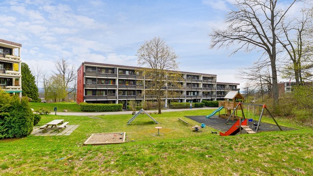 Store, grønne fellesarealer med lekeplass og sittegrupper, pent opparbeidet for beboerne.