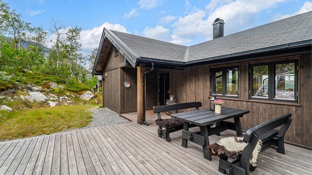 Uteplassen bak hytta ligger lunt til i terrenget med god plass til langbord.