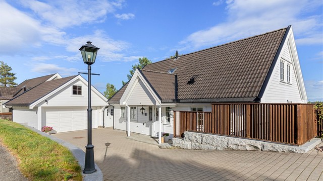 Steinbelagt gårdsplass med god plass til biloppstilling foran garasjen og boligen.
