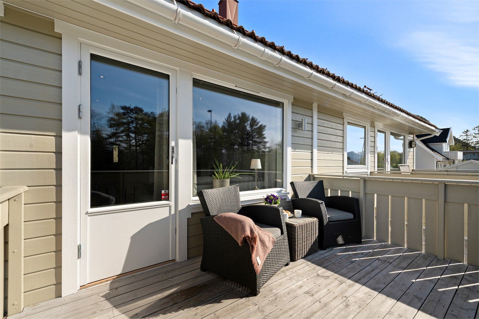 Balkongen har gulv av terrassebord og utebelysning.