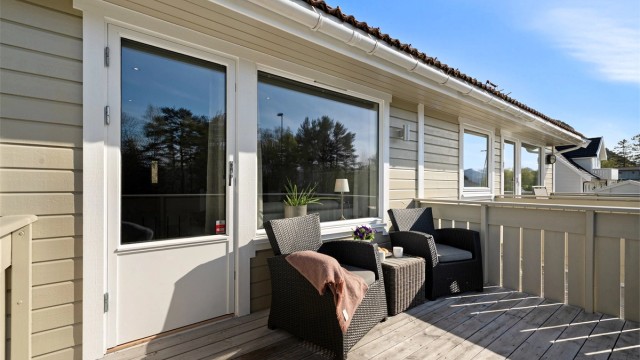 Balkongen har gulv av terrassebord og utebelysning.