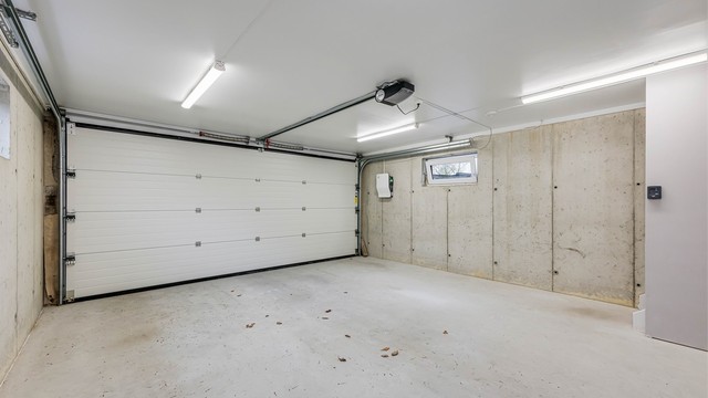 Garasjens 1. etasje er på 37 kvm med dobbel ledd port og Elbil lader installert på veggen.