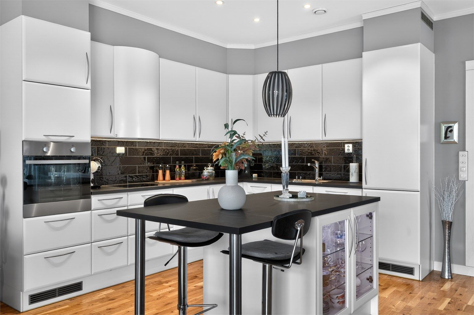 Kjøkkenet ligger naturlig tilbaketrukket fra stuen og er innredet med lyse, slette flater og benkeplate i kontrast. 