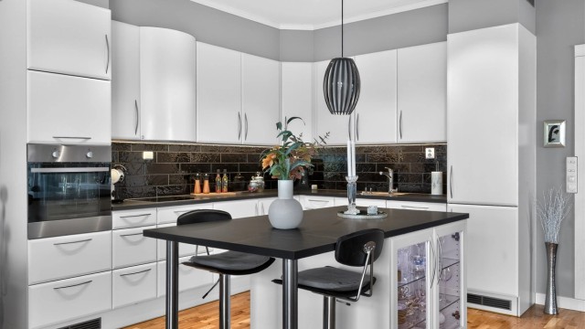 Kjøkkenet ligger naturlig tilbaketrukket fra stuen og er innredet med lyse, slette flater og benkeplate i kontrast.