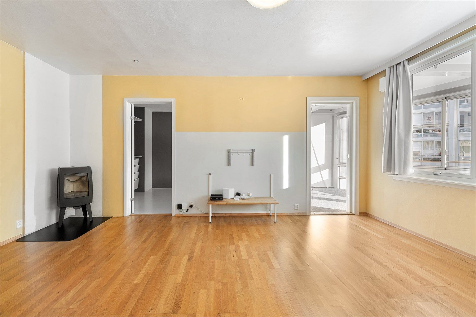 Lys stue med peisovn. Adkomst til soverom samt utgang til innglasset balkong