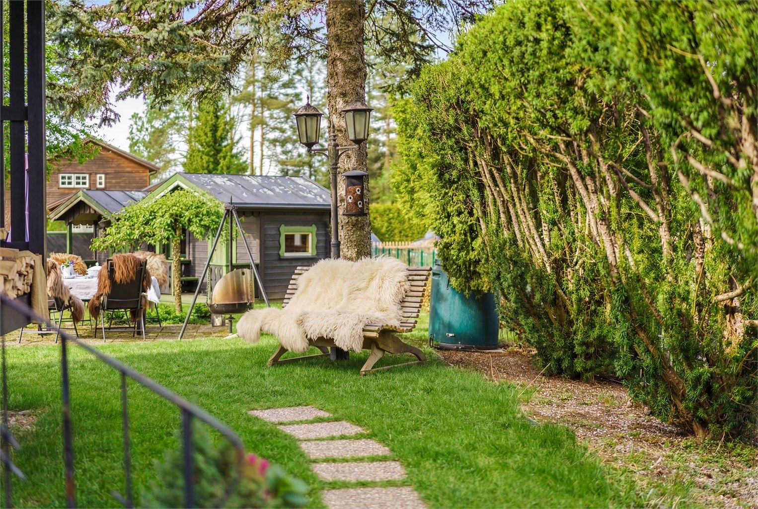 Eiendommen har flere trivelige utesoner med sitteplasser, beplantning, anneks m.m. Bildet har AI-redigert plen. 