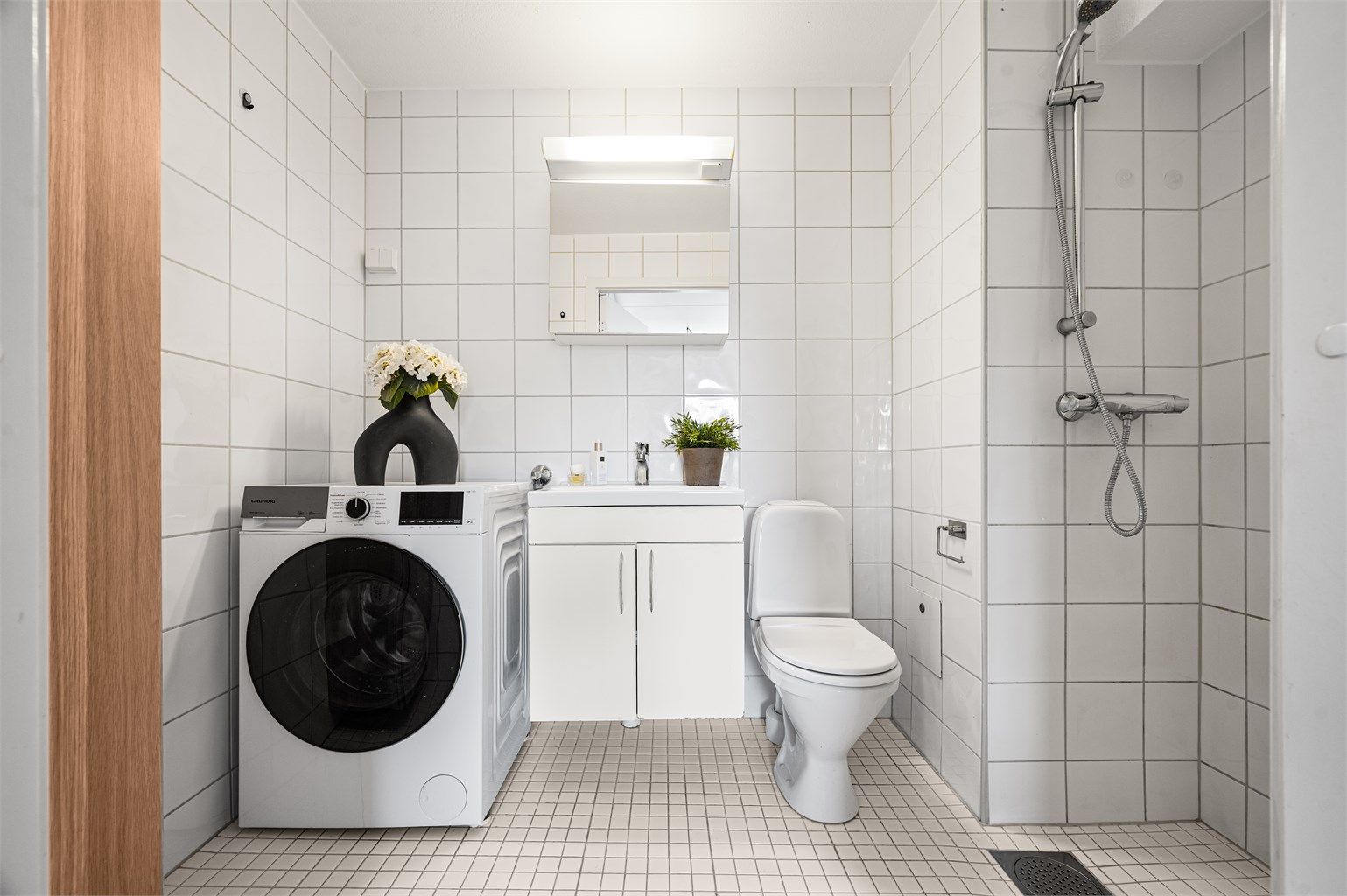Et flislagt bad med gulvvarme og opplegg for vaskemaskin gir en praktisk og komfortabel hverdag.