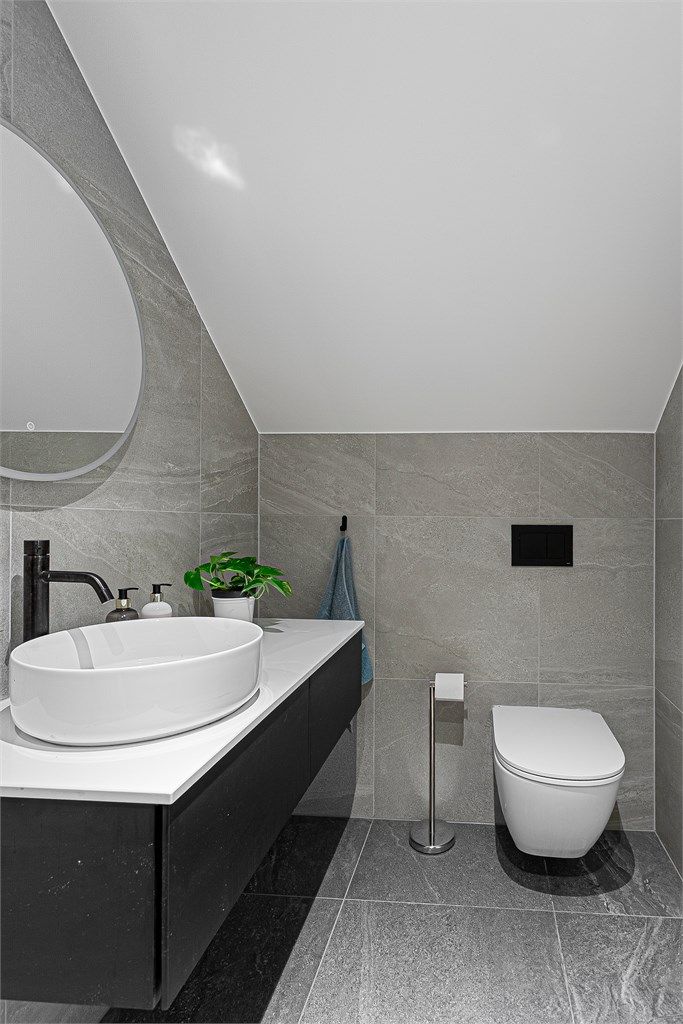 Pent flislagt bad 1 fra 2023 med adkomst fra loftstue. Downlights i himlingen. Innredet med vegghengt servantinnredning med skuffer og ovenpåliggende servant. Speil med sidelys. 