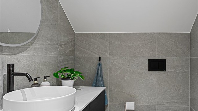 Pent flislagt bad 1 fra 2023 med adkomst fra loftstue. Downlights i himlingen. Innredet med vegghengt servantinnredning med skuffer og ovenpåliggende servant. Speil med sidelys.