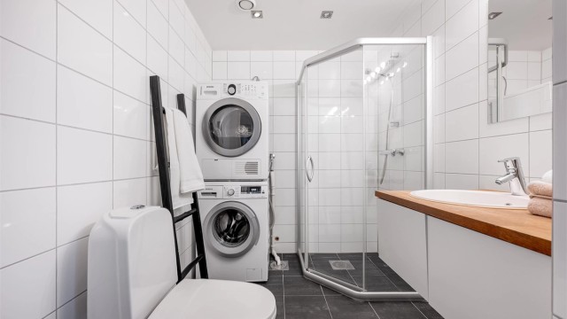 Fint helfliset bad av godt størrelse med varme i gulv. Det er dusjhjørne, toalett og servant med oppbevaringsplass i skuffer. Stort speil på vegg. Opplegg for vaskemaskin samt plass til tørketrommel om man skulle ønske det. Et fint og stilrent baderom.