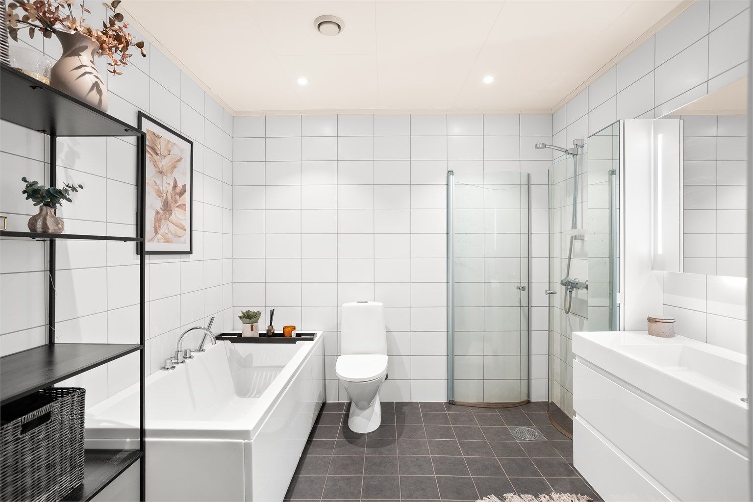 Helflist bad med elektrisk gulvvarme, badekar og en separat dusjnisje med innfellbare glassdører.