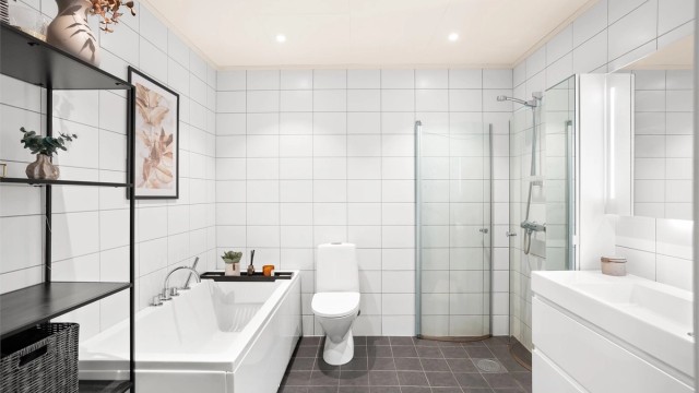 Helflist bad med elektrisk gulvvarme, badekar og en separat dusjnisje med innfellbare glassdører.