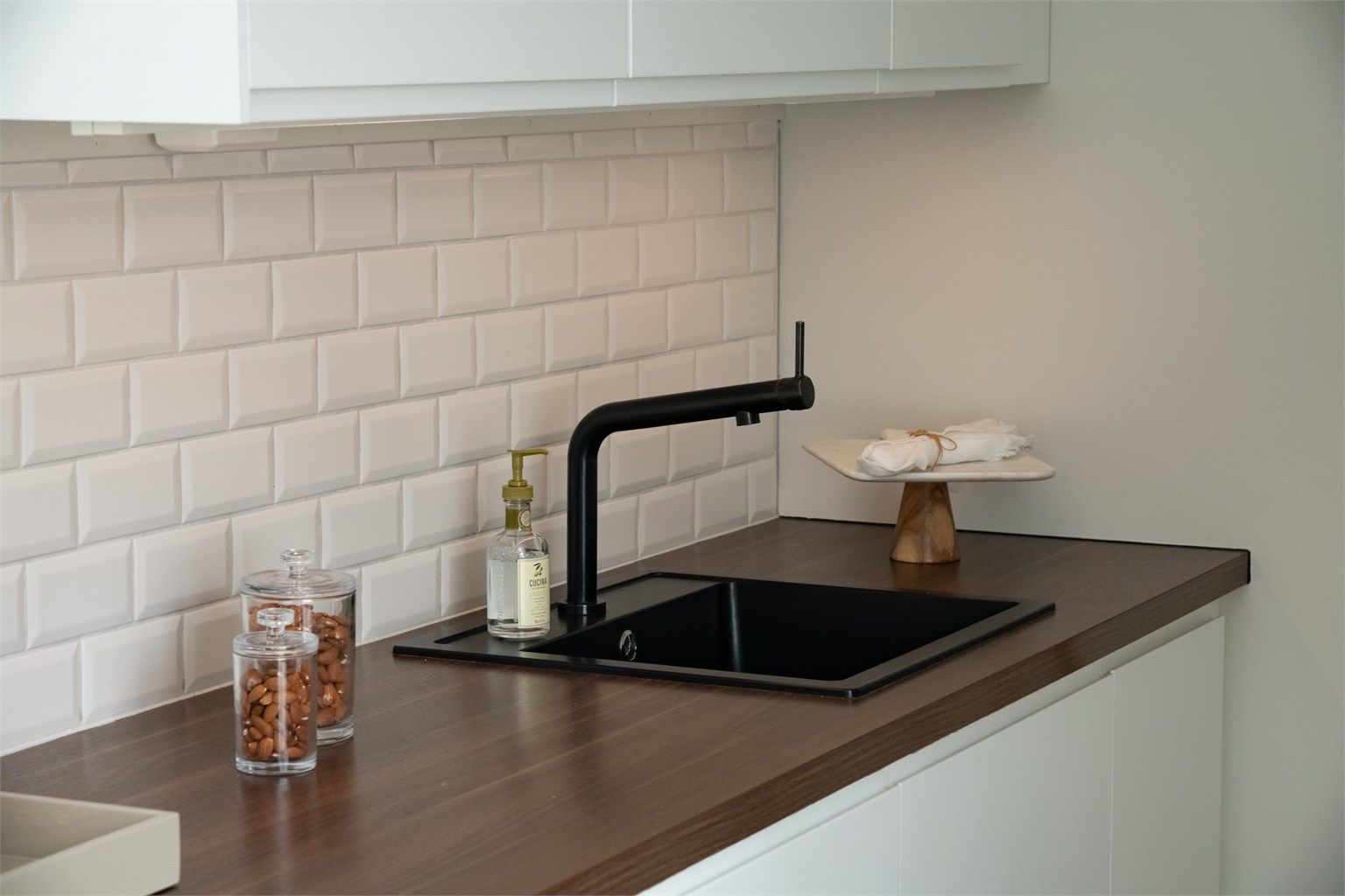 Vask med ett-greps armatur, belysning og stikkontakter under overskap. 