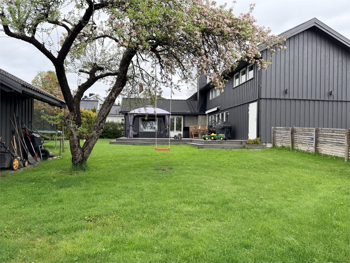 Pent opparbeidet hage med stor og flat gressplen og diverse beplantninger