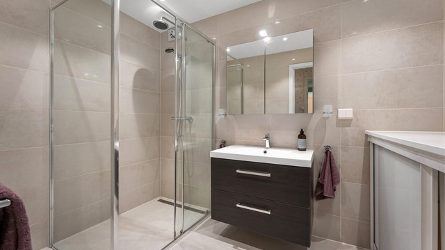 Badet i første etasje er flislagt og utstyrt med gulvvarme, downlights og dusjhjørne med regndusj.