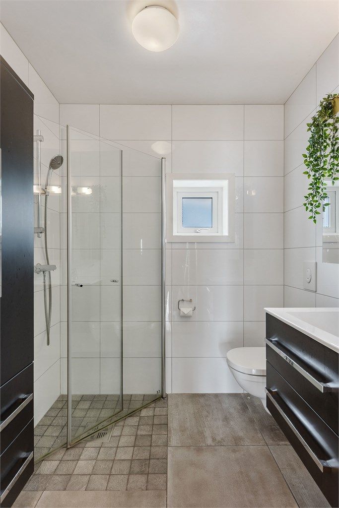 Badet i andre etasje er også flislagt og utstyrt med  med servantinnredning, dusjhjørne og vegghengt wc.