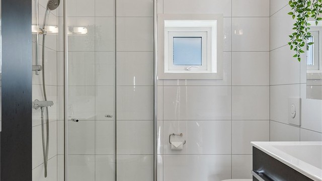 Badet i andre etasje er også flislagt og utstyrt med med servantinnredning, dusjhjørne og vegghengt wc.