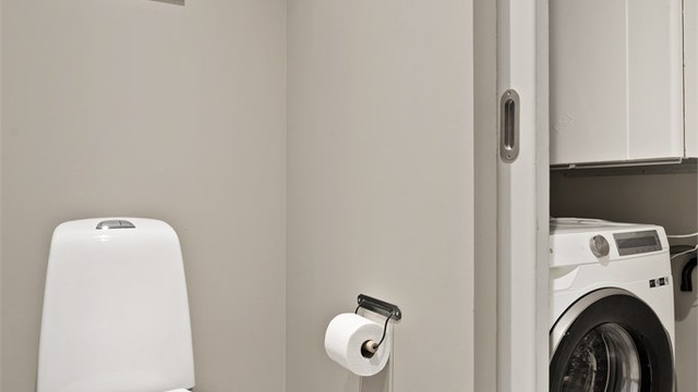 Innenfor toalettrommet er det et flislagt vaskerom med gulvvarme og opplegg for vaskemaskin
