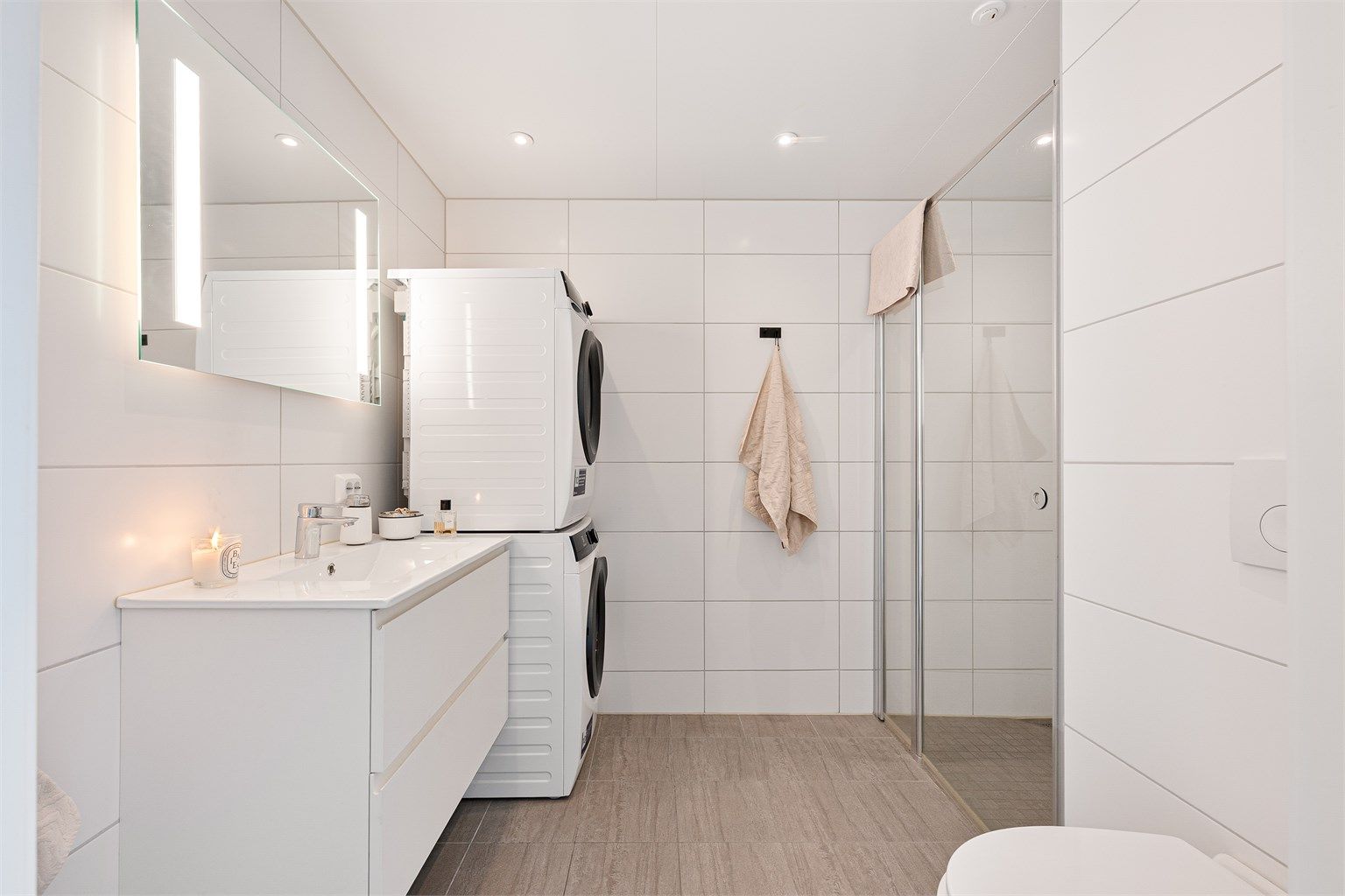 Badet er flott helfliset med fine fliser på gulv og på vegg. Det er spotter i tak som gjør badet ekstra lyst og det er i tillegg speil på vegg over servant med innfelt lys. 
