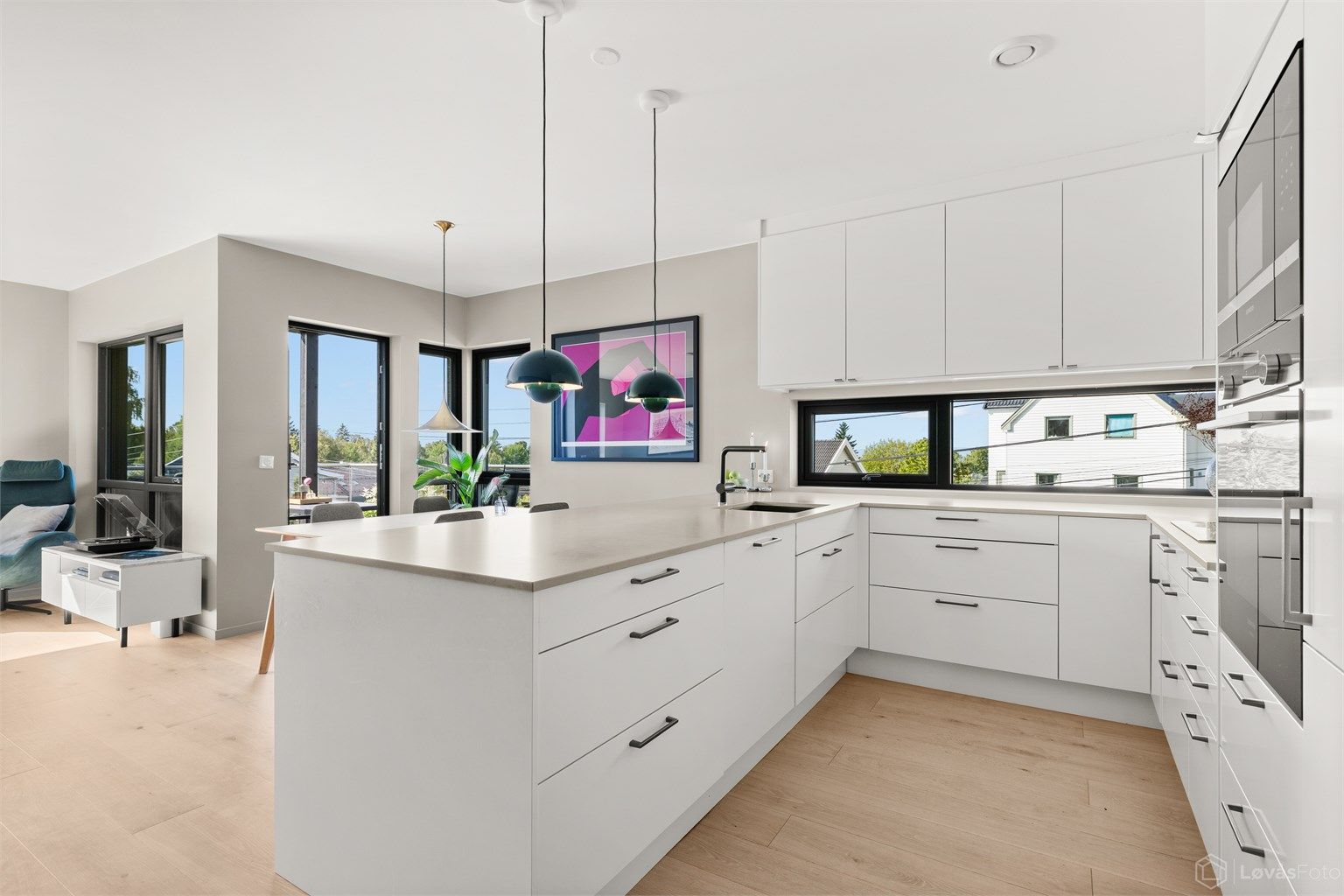 Innredningen har glatte fronter, påkostet benkeplate i polert Silestone-kompositt, og god skap- og benkeplass, noe som gjør kjøkkenet både praktisk og innbydende.