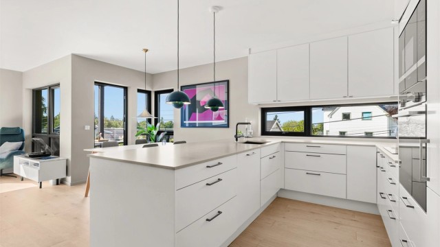 Innredningen har glatte fronter, påkostet benkeplate i polert Silestone-kompositt, og god skap- og benkeplass, noe som gjør kjøkkenet både praktisk og innbydende.