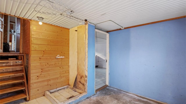 Kjellerrom med synlig betong på gulv og trappeadkomst opp til første etasje.