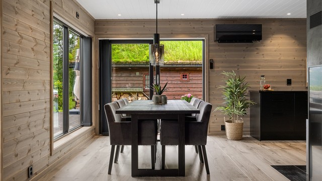 Det åpne stue- og kjøkkenrommet fremstår som hyttas naturlige samlingspunkt – en harmonisk kombinasjon av moderne design, varme materialvalg og store vindusflater som slipper både lys og naturen inn