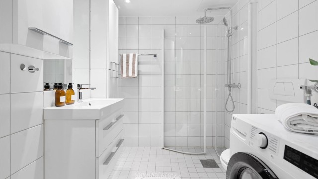 Badet er praktisk innredet med vegghengt servantskap med skuffer, ovenpåliggende servant og speil med tilhørende veggskap og vegghengt toalett med innebygd sisterne.