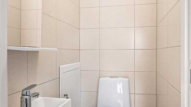 Separat og praktisk toalettrom er etablert ved siden av badet. Rommet er innredet med servantmøbel og speil.