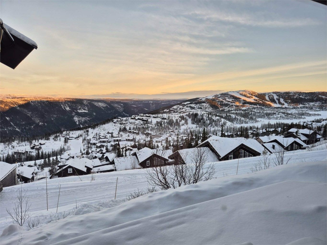Kveldshimmel over det snødekte hyttefeltet og fjellene.