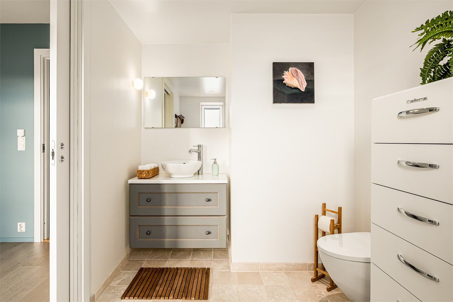 Badet er pent flislagt på gulv, med malte overflater på veggene. Det er gulvvarme, og himlingen har malt, slett flate med downlights.
