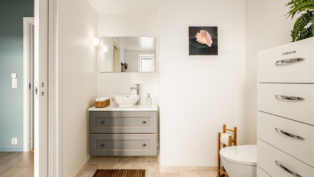 Badet er pent flislagt på gulv, med malte overflater på veggene. Det er gulvvarme, og himlingen har malt, slett flate med downlights.