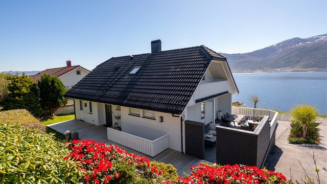 Fasaden har liggende bordkledning og taket er tekket med betongtakstein.