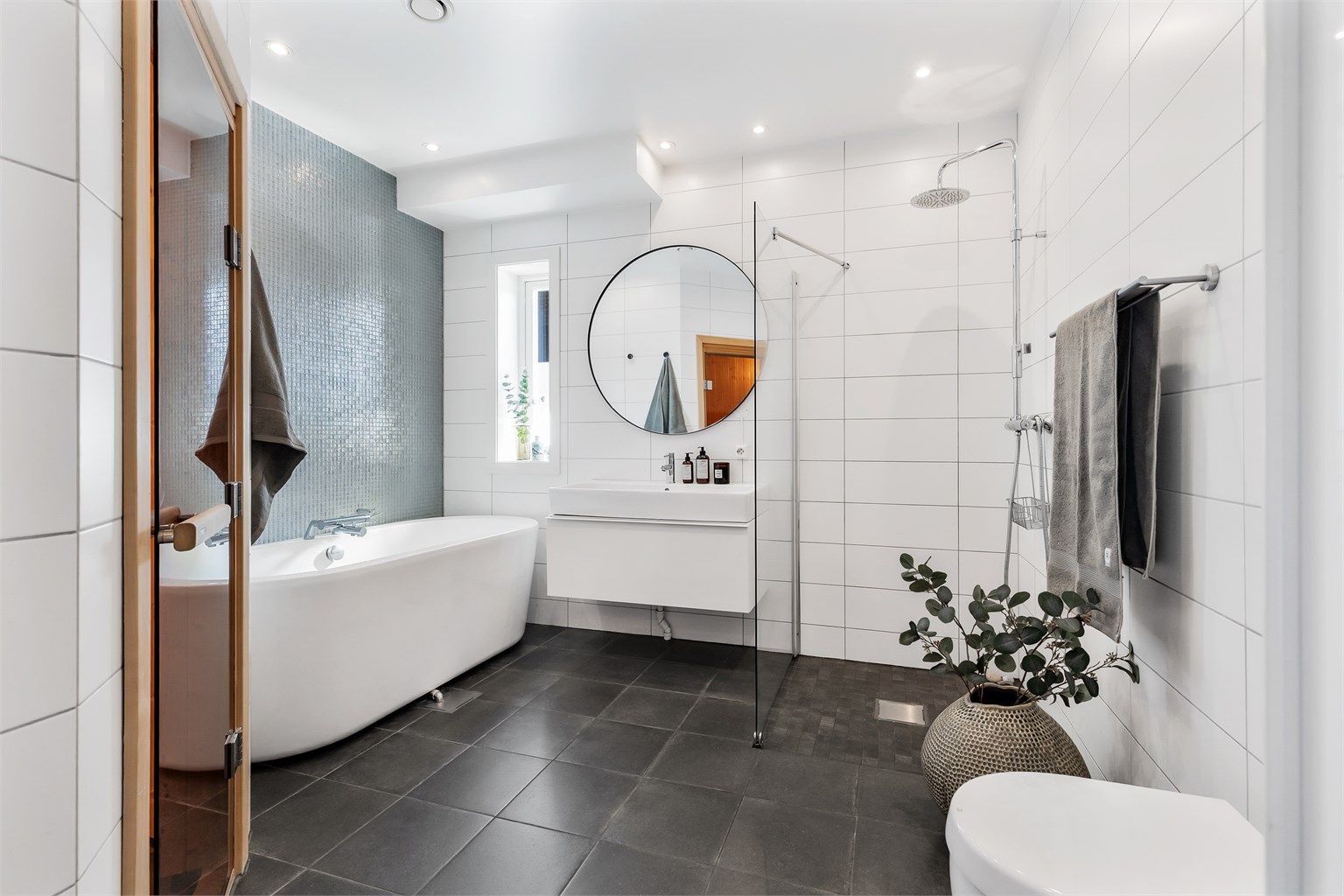 Baderom med flislagt gulv med varme og flislagte vegger. Nedsenket himling med downlights. Vegghengt servantskap i slett utførelse. Ovenpåliggende servant med ett-greps armatur. Dusjsone med skillevegg i glass. Dusjarmatur tilkoblet hånddusj og regndusj.