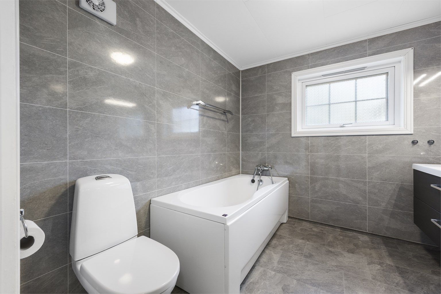 Badet i 1. etasje er utstyrt med badekar, baderomsplater på veggene og gulvvarme.