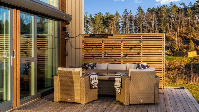 UTEPLASS MED EKSTRA DIMENSJON: I hjørnet utenfor stuen er det laget en skjermet uteplass. Den er møblert med lave lounge-sofaer. Den store markisen gir sitteplassen en ekstra dimensjon.