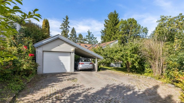 Frittstående garasje med carport og EL-billader. Gårdsplass med belegningsstein.
