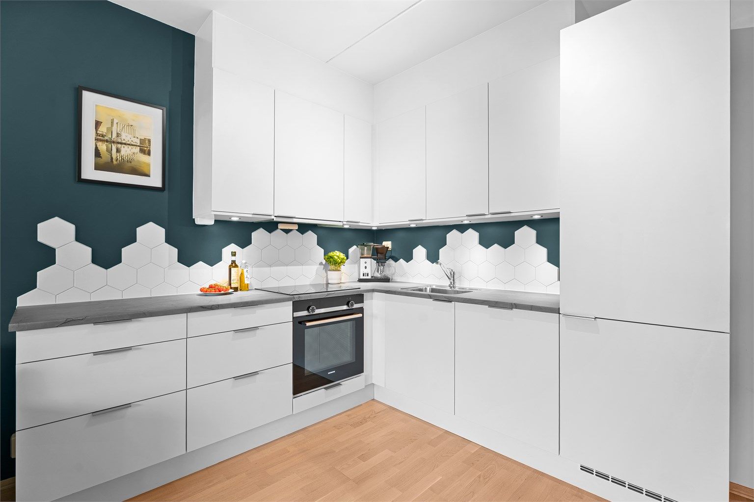 Kjøkkenet er minimalistisk og har integrerte hvitevarer som koketopp, stekeovn, oppvaskmaskin og kjøleskap/frys. De flotte hexagon flisene som backsplash skaper en flott kontrast og spill. 