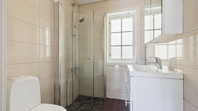 Badet i andre etasje ble også modernisert i 2015. Her er det dusjhjørne med rullestein på gulvet.