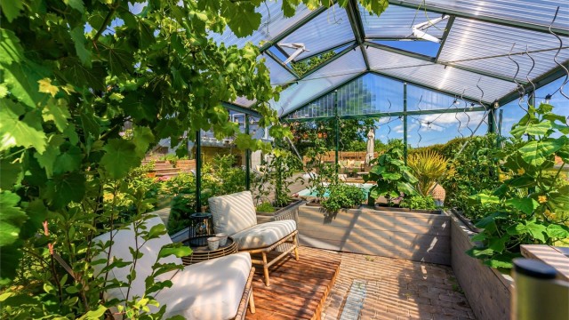 Inne i drivhuset er det god plass til både planter og en liten sittegruppe.
