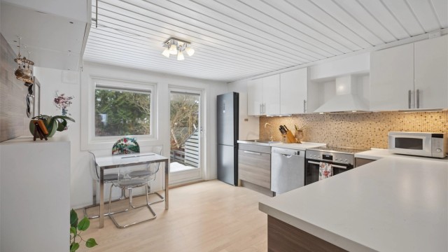 Det er god skap- og benkeplass, og kjøkkenet har også romslig plass til spisebord med et hyggelig utsyn mot hagen. Dette gir en lys og trivelig spiseplass med fin kontakt mellom inne- og uteområdet.