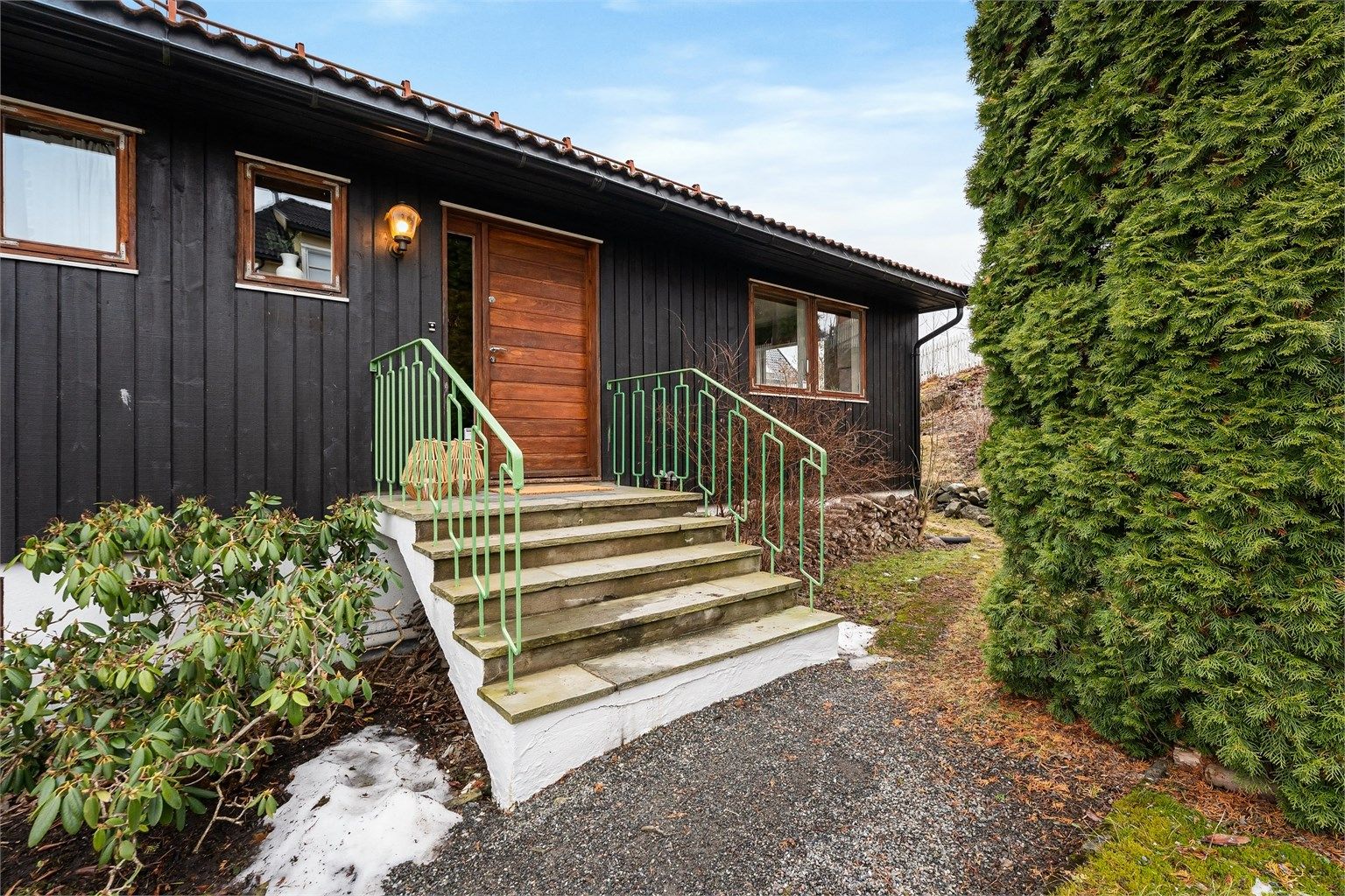 Hovedinngangen har et praktisk overbygg og leder inn til boligens første etasje.