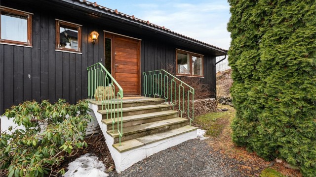 Hovedinngangen har et praktisk overbygg og leder inn til boligens første etasje.