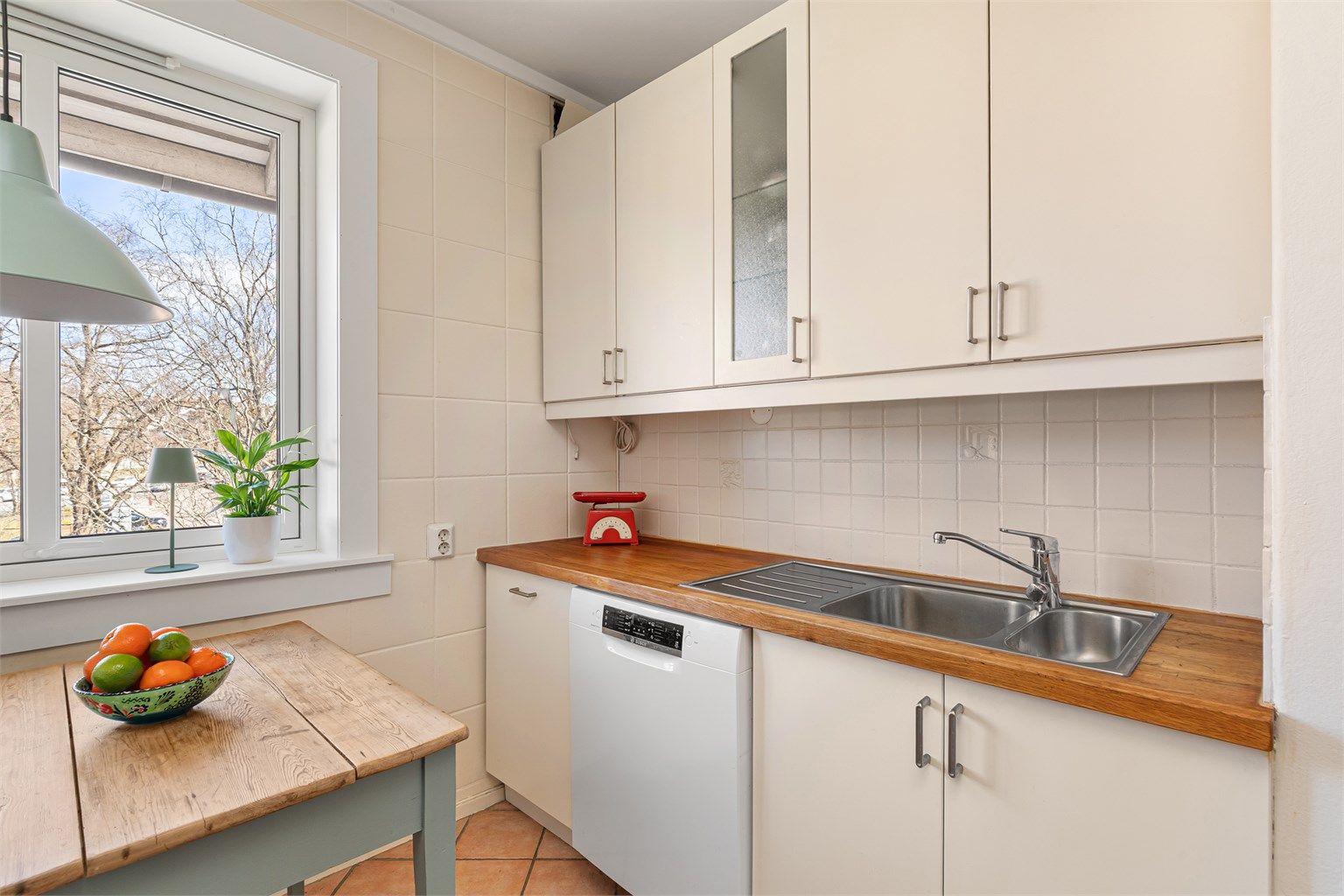 Kjøkkeninnredning har slette fronter som står i stil til fargetonene på veggflatene og benkeplate i tre