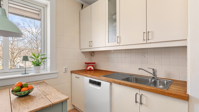 Kjøkkeninnredning har slette fronter som står i stil til fargetonene på veggflatene og benkeplate i tre