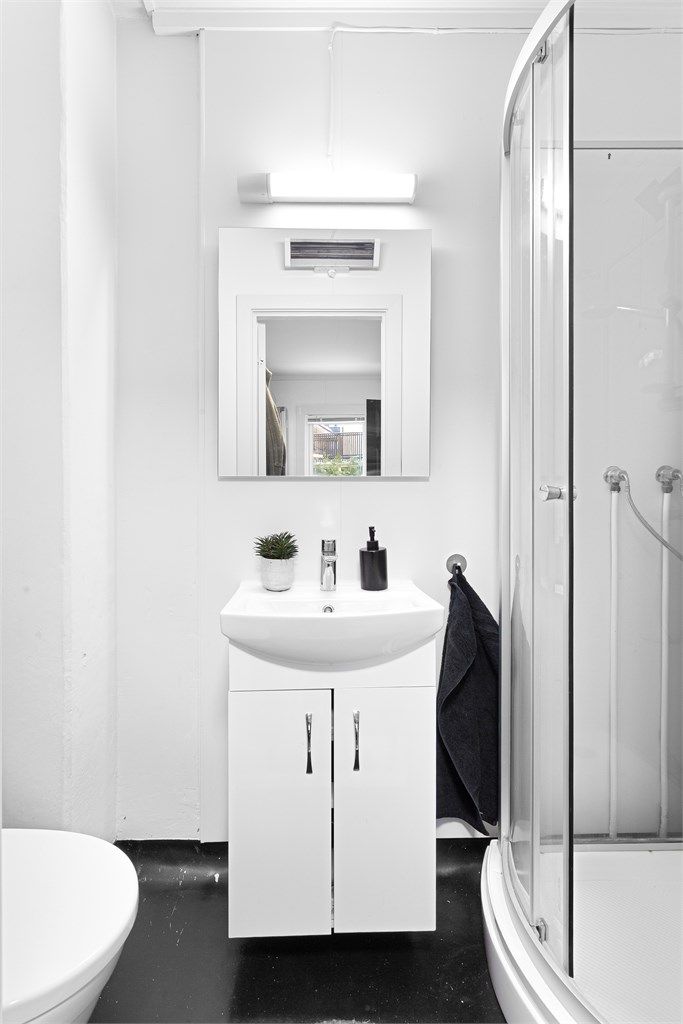 Badet er utstyrt med dusjkabinett, servant med underskap og gulvstående toalett.